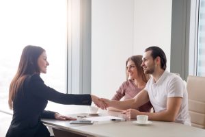 Happy young couple making real estate deal, handshake with agent