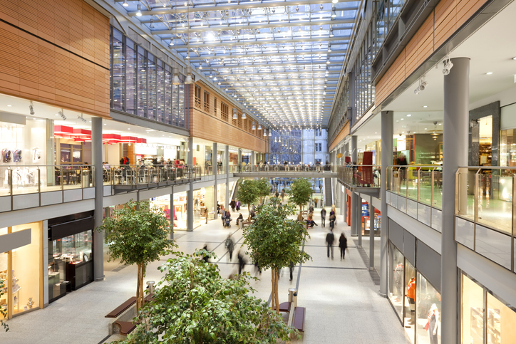 Image taken inside a shopping mall. There are lots of people walking around going to stores, buying things and consuming food and beverages. There are two floors with shops and boutiques. The ceiling is glass. The architecture is very modern and new and the general feel of the images is bright, clean, safe and positive.