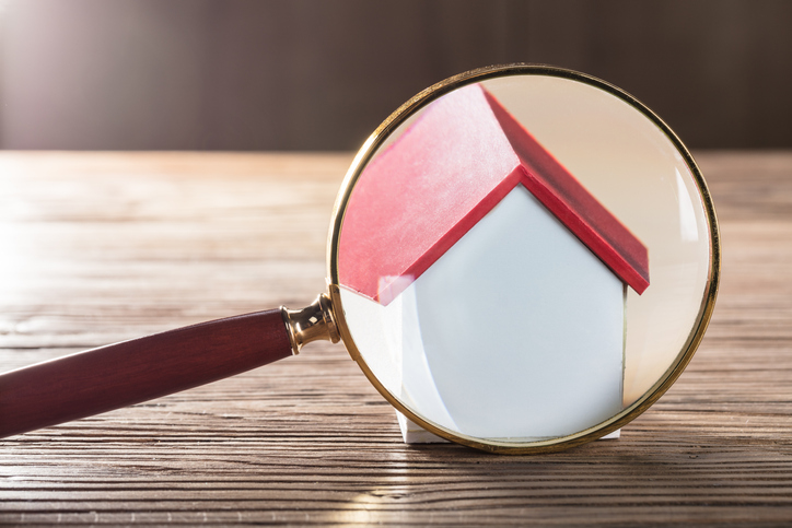 Close-up Of A House Model Seen Through Magnifying Glass On Wooden Table