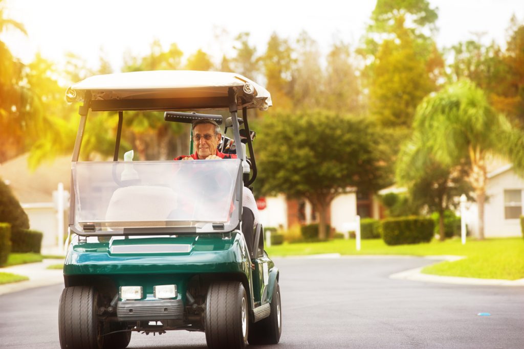 old man driving a golf cart